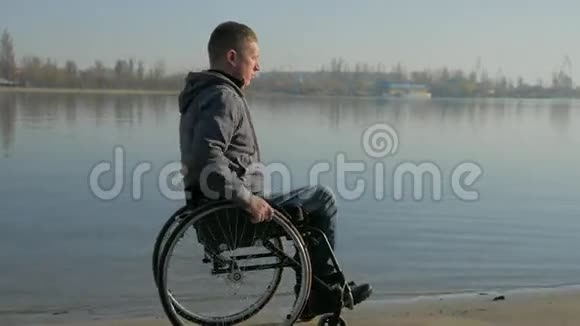轮椅上的残疾人骑着沙子坐着轮椅在河边视频的预览图