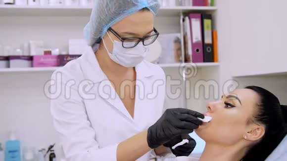 在诊所的美容室里医生用无菌餐巾纸擦拭病人的嘴唇然后注射透明质酸视频的预览图