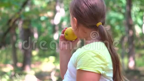 小女孩在大自然的公园里吃一个红苹果视频的预览图