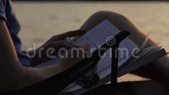 年轻的博客作者在日落时在折叠椅上写文章视频的预览图