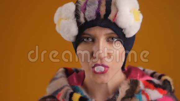 特写女郎时尚模特化妆专业在橙色背景下可怜巴巴地嚼口香糖视频的预览图