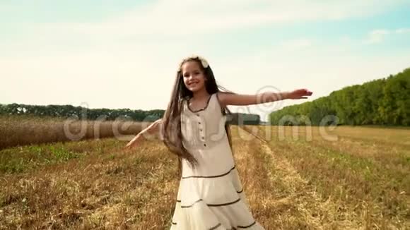 黑发女孩穿着一件长裙子慢动作穿着白色裙子的女孩在田野上跳舞快乐的孩子视频的预览图