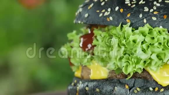 牛肉和黄瓜的汉堡木制的生菜叶子和蔬菜背景模糊的黑色面包视频的预览图