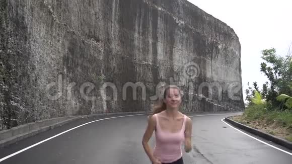 在岩石悬崖附近的路上慢跑的女人视频的预览图