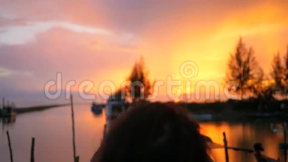 年轻的混血女孩在渔人码头用手机拍摄美丽的日落高清慢速运动泰国视频的预览图