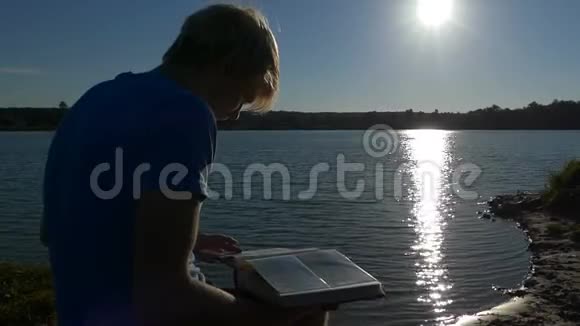 金发男人坐在侧面看着湖岸上的照片视频的预览图