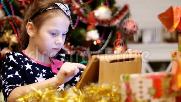 穿着漂亮裙子的可爱金发女孩正在平板电脑上打印一封致圣诞老人的信旁边是礼物和圣诞树视频的预览图
