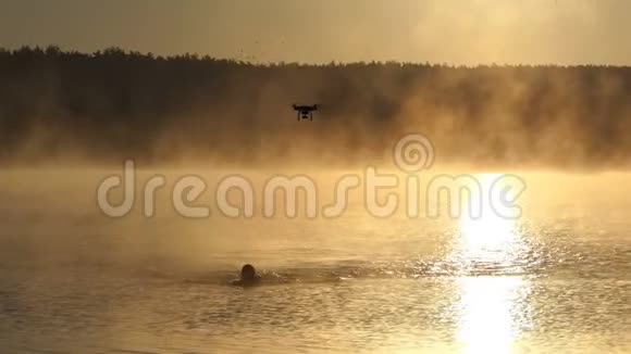活泼的人在一个金色的湖里爬行一架无人驾驶飞机正在船上飞行视频的预览图