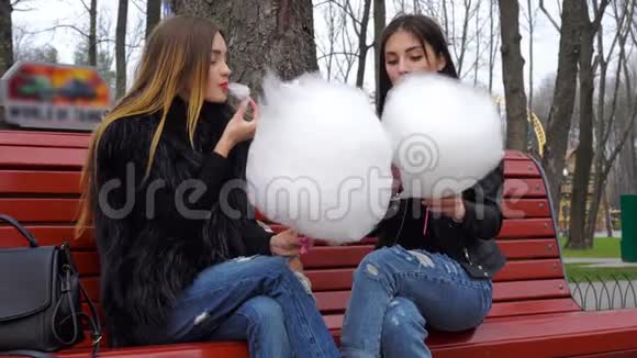两个女孩在长凳上玩吃棉花糖视频的预览图