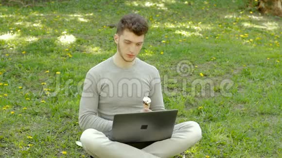 体贴的人在公园里用笔记本电脑工作吃冰淇淋视频的预览图