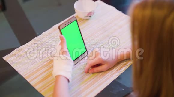 年轻的白种人金发碧眼左手骨折看着绿色的智能手机屏幕视频的预览图