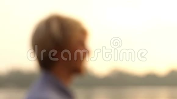 在斯隆莫日落的河岸上人们站着整理自己的头发视频的预览图
