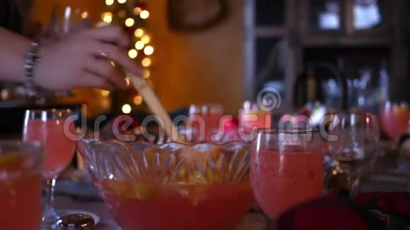 女人在圣诞餐桌上从大碗里舀起柠檬水装杯子视频的预览图