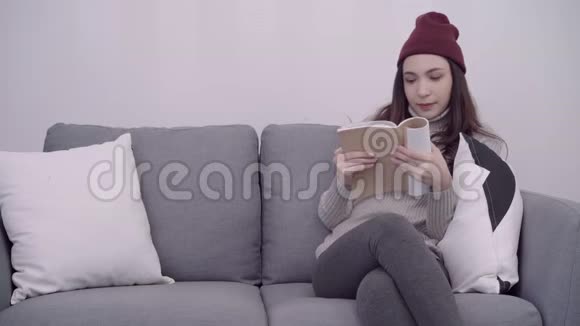 一幅美丽迷人的亚洲女人在家客厅放松时坐在沙发上看书的肖像视频的预览图