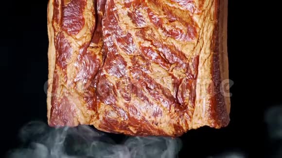 在黑色背景的烟雾中熏出多汁和美味的大块培根烹饪肉猪肉视频的预览图