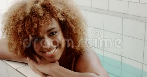 黑色混血金发女人在游泳池游泳后休息视频的预览图
