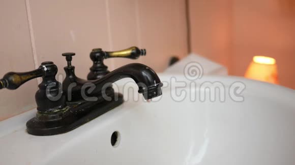 一只古董水龙头留在浴室里滴在水槽里视频的预览图