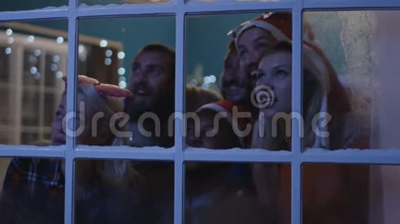 圣诞期间兴奋的朋友们在窗外张望视频的预览图