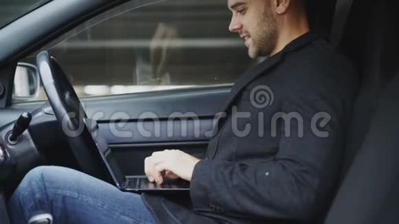 笑容可掬的男人在户外坐在车里打手提电脑视频的预览图