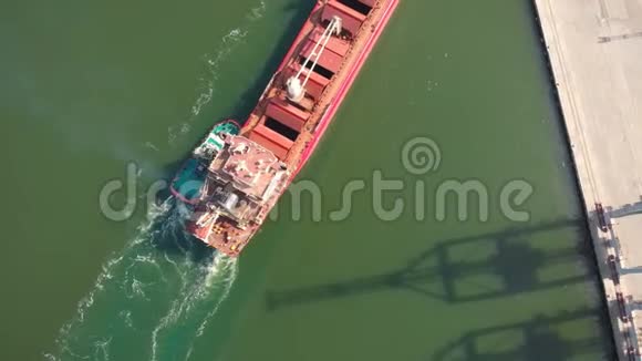 一艘大型散货船带着拖船进入货物港空中镜头4K视频的预览图