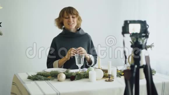 有魅力的开朗的女人坐在餐桌前在视频博客上录制关于相机上食物装饰设计的视频视频的预览图