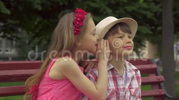 小女孩和板凳上的男孩分享秘密视频的预览图