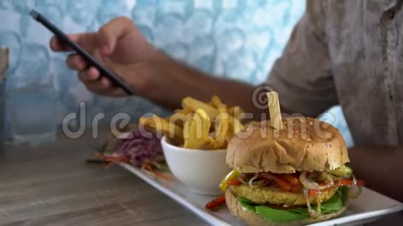 男人吃汉堡和法国薯条和聊天电话视频的预览图