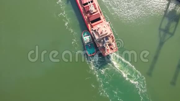 一艘大型散货船带着拖船进入货物港空中镜头4K视频的预览图
