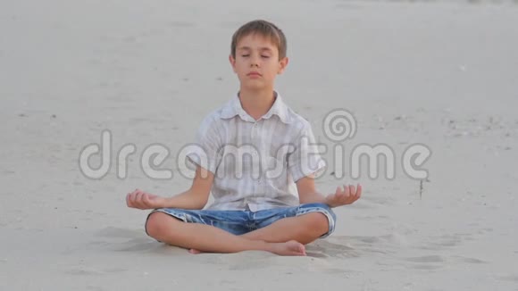 夏天男孩坐在沙滩上打坐视频的预览图