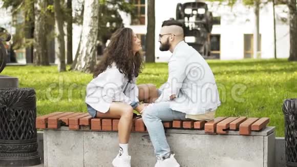 情侣接吻坐在公园的长凳上互相看着视频的预览图
