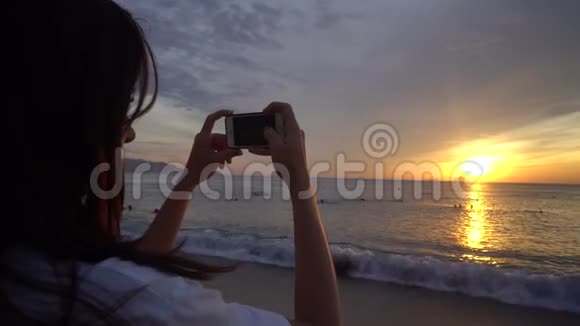 女人在智能手机上拍摄美丽的日出视频的预览图