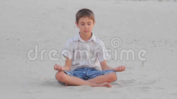 夏天男孩坐在沙滩上打坐视频的预览图