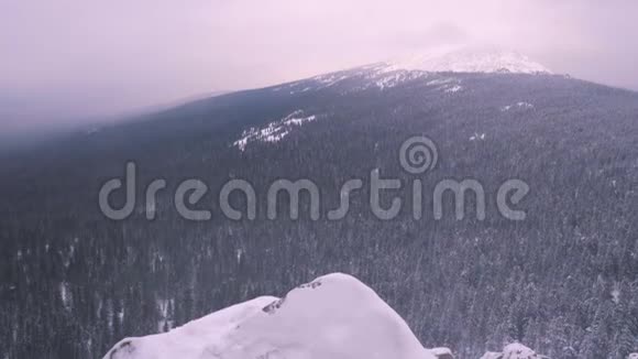 一个年轻人一个游客站在一座白雪覆盖的山的边缘欣赏山顶视频的预览图