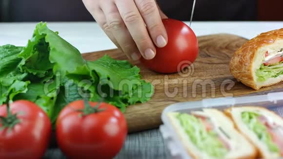 女人在木板上切西红柿背景上的午餐盒里有三明治准备工作三明治学校视频的预览图