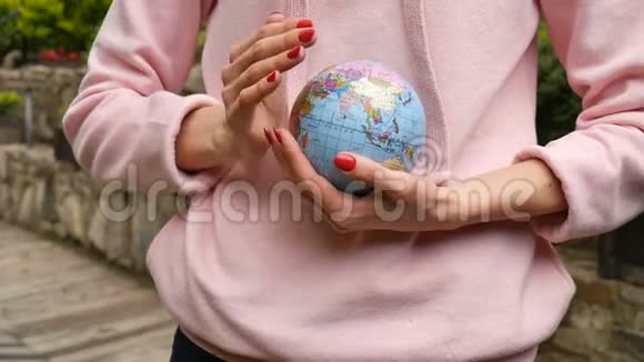 年轻的女青少年穿着粉色便服戴着红色的指甲手里拿着一个地球仪名字很精致视频的预览图