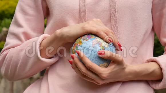 年轻的女青少年穿着粉色便服戴着红色的指甲手里拿着一个地球仪名字很精致视频的预览图