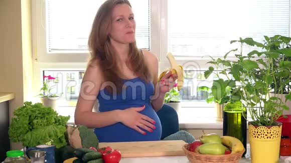 美丽的白种人孕妇在厨房吃香蕉视频的预览图