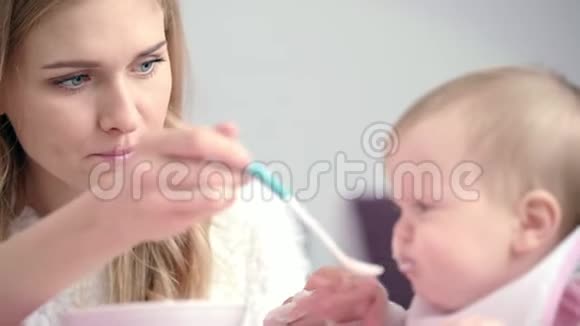 年轻的母亲喂养婴儿年轻妈妈用勺子喂孩子视频的预览图