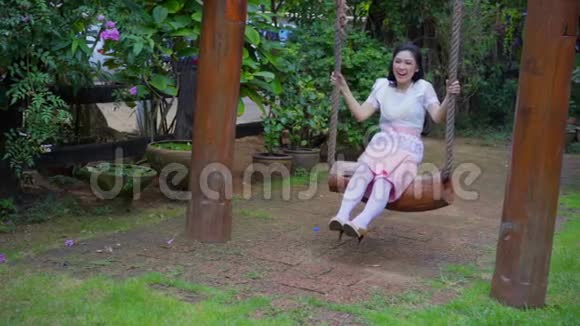穿着泰国传统服装的快乐年轻女子在木制秋千上放松视频的预览图