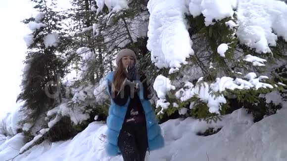 年轻漂亮的女孩走在白雪皑皑的冬林里她快乐而平静一个女孩站在一个大雪覆盖的地方视频的预览图