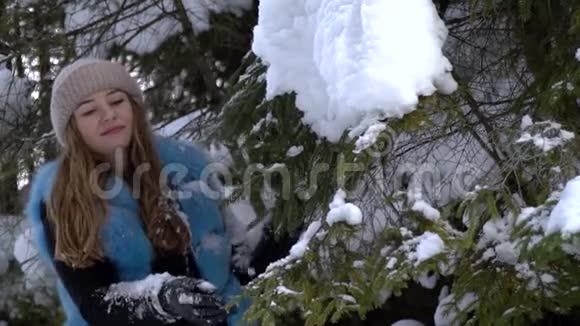 年轻漂亮的女孩走在白雪皑皑的冬林里她快乐而平静一个女孩站在一个大雪覆盖的地方视频的预览图