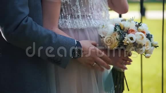 新郎把手放在新娘的腹部上新娘手里拿着花双手特写视频的预览图
