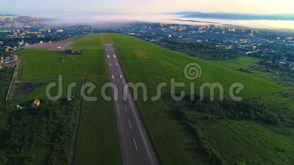 向跑道发射无人机两边的绿色田野晨雾笼罩城市视频的预览图
