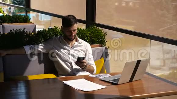 房地产经纪人通过智能手机交谈并与笔记本电脑在餐桌上工作视频的预览图
