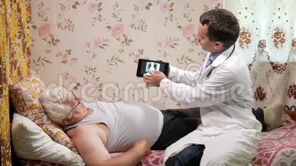 一位男医生在家看望病人它显示了平板电脑上X射线的结果那个人躺在床上视频的预览图