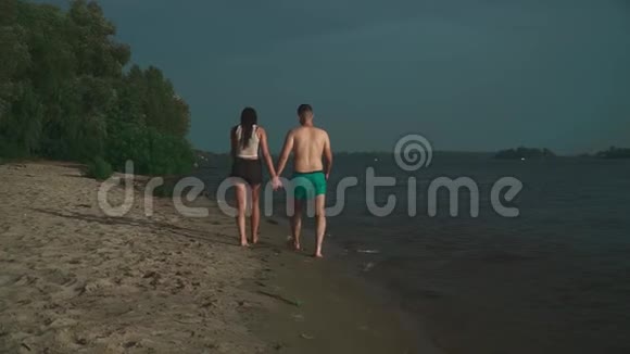 年轻人和一个美丽的黑发女人正沿着河岸散步视频的预览图