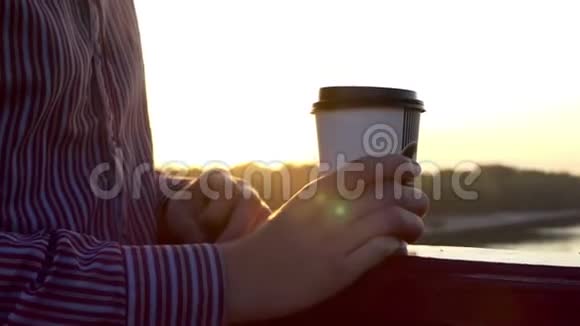 年轻人站在纸杯里喝咖啡在桥上享受日落视频的预览图