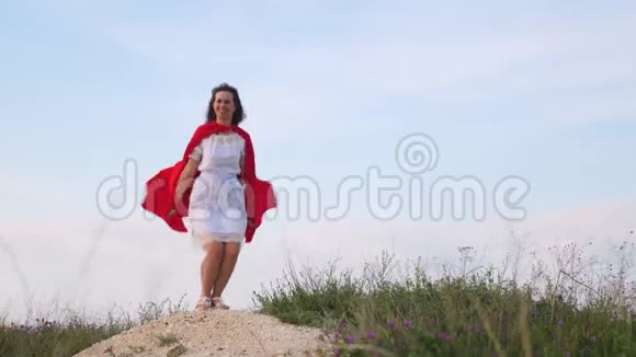 年轻的女人穿着红色的斗篷表现着梦想女孩梦想成为超级英雄美丽的超级英雄视频的预览图