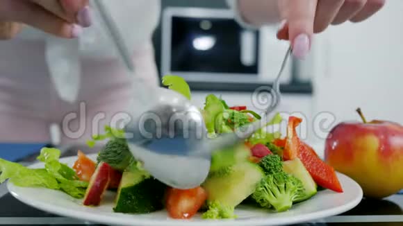 素食手拿刀叉混合新鲜沙拉和橄榄油视频的预览图