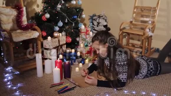 可爱的小女孩留着长长的头发戴着圣诞礼物和蜡烛给圣诞老人写了一封信视频的预览图